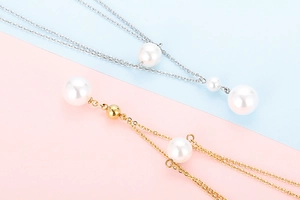 Detail of layered gold and silver chains with elegant white pearls on pastel background