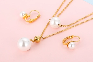 Detailed close-up of 18K gold plated pearl necklace and matching earrings on pink background