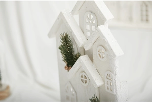 Detailed macro view of white Christmas wooden house with glitter snow and mini pine tree decor