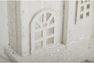 Detailed macro view of white wooden Christmas house with glittery silver base decoration