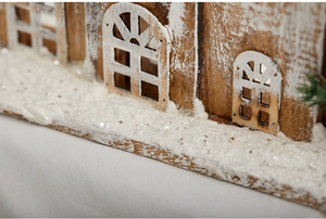 Close-up of white snow texture and natural wood grain on a miniature Christmas house