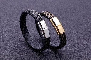 Close-up of black braided leather bracelets with gold and silver magnetic steel clasps
