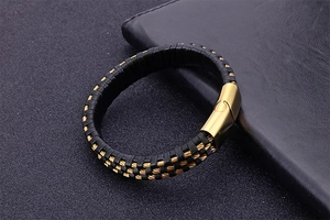 Detail of black braided leather bracelet with a polished gold magnetic clasp for men
