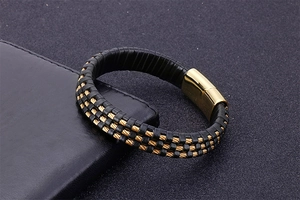 Detail of black leather braided bracelet featuring a gold magnetic clasp with wire inlay