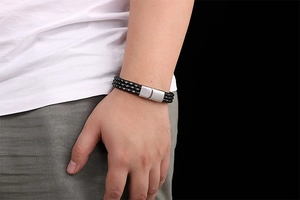 Detail of black braided leather bracelet with silver matte magnetic buckle on wrist