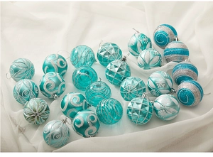 Detailed view of teal and silver Christmas baubles with glitter on white fabric