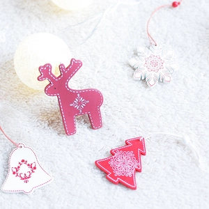 Wooden Nordic Christmas ornaments set with elk and snowflake shapes on a plush white rug