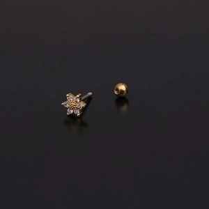 Macro detail of a gold flower stud earring with sparkling zircons on a black surface