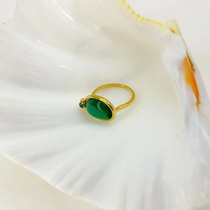Detail of 18K gold plated ring with emerald green stones set inside a white seashell