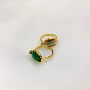 Close-up of 18K gold plated rings with emerald green and light pink oval gemstones