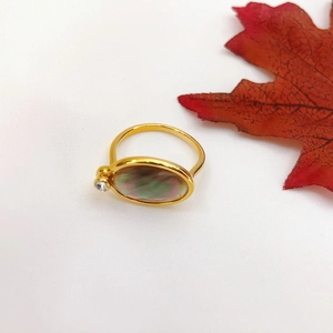 Detail of 18K gold-plated ring with oval mother of pearl and autumn maple leaf