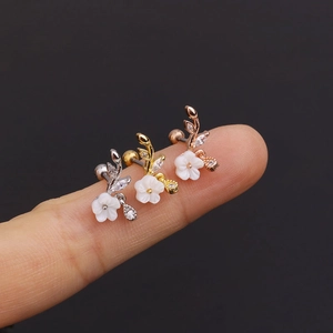 Three floral stud earrings in silver, gold, and rose gold finishes on a hand display