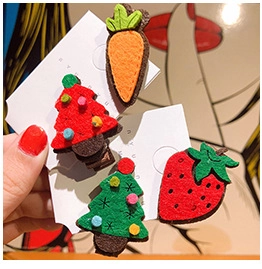 Close-up of four felt hair clips featuring carrot, strawberry, and Christmas tree designs