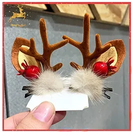 Detail view of reindeer antler hair clips with plush pom-poms and red berry accents