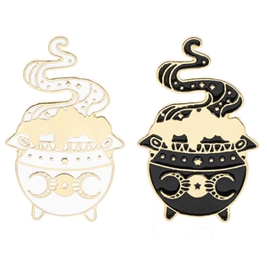 Detail of gothic witch cauldron enamel pins with moon symbols in black and white gold finish
