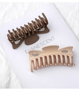 Detail of matte large hair claw clips in brown and beige colors on a magazine