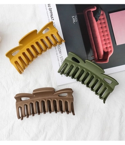Macro detail of large matte hair claws in earth tones with hollowed side design