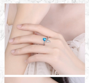 Close-up of heart-shaped blue stone and crystal fishtail detail on open silver ring