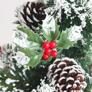 Snow-covered Christmas mini tree with red berries, pine cones and holly leaf decor