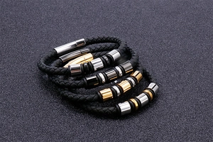Detail of multi-layered black braided leather bracelets with silver and gold magnetic clasps