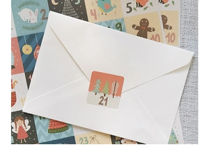Close-up of numbered Christmas advent calendar stickers sealing a white gift envelope