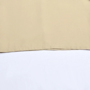 Detailansicht des beigen Kleidsaums mit Fokus auf Nähte und gewebte Stoffstruktur