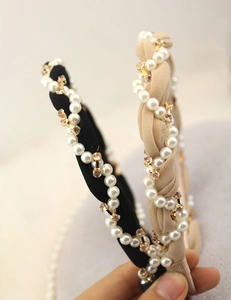 Close-up of wavy fabric headbands with pearl and rhinestone embellishments in soft lighting