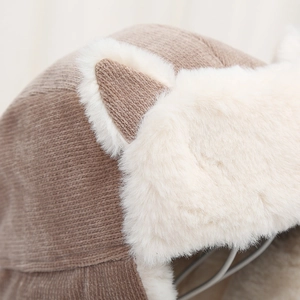 Detailed macro view of the warm brown knit texture and white faux fur on the cat ear hat