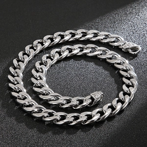 Macro detail of high-polish silver Cuban chain necklace on black textured background