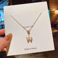 Dettaglio di una collana a farfalla dorata con inserto in madreperla su scheda display