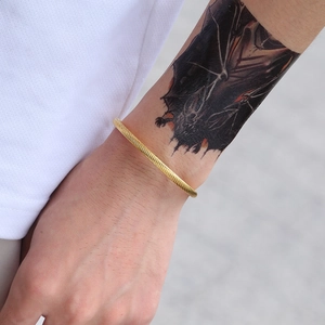 Men's golden open cuff bracelet in stainless steel with twill texture worn on wrist