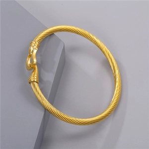 Top view of a gold-colored stainless steel twisted rope bracelet on a gray background