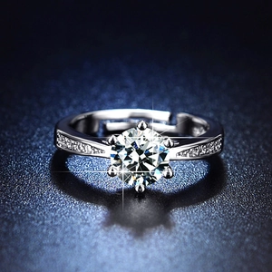 Macro shot of silver six-prong moissanite ring with side diamonds on blue background