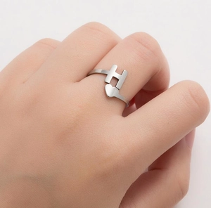 Close-up of silver stainless steel ring with H-letter and heart detail on finger