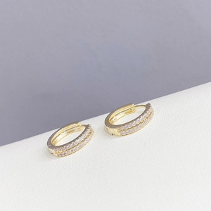 Detail of gold-plated double-row crystal huggie earrings with a secure hinged closure
