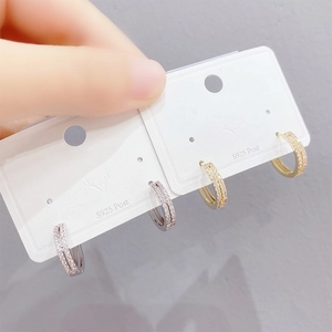 Macro detail of gold and silver double row crystal hoop earrings on jewelry card
