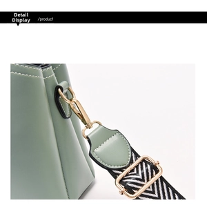 Detail of golden metal hook on Morandi green leather bag with woven shoulder strap