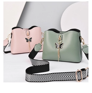 Close-up of shell bags in pink and green with butterfly charms and striped straps