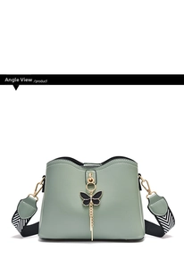 Detail of mint green crossbody bag with black butterfly charm and V-patterned strap
