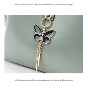 Detail of green leather shell bag featuring black enamel butterfly charm and gold hardware
