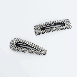 Detalle cercano de pinzas para el cabello con diamantes de imitación y base negra.