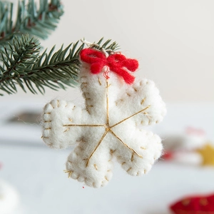 Christmas wool felt snowflake hanging ornament with red bow on a festive tree