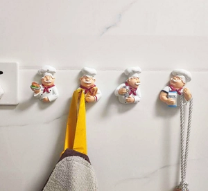 Set of four creative chef-shaped wall hooks mounted on white marble kitchen tiles