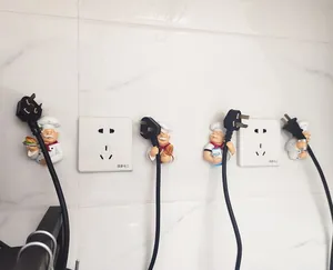Detail of cartoon chef plug hooks showing cable management on white marble wall