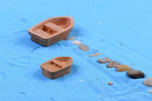 Macro detail of miniature resin rowboats on blue sand for moss terrarium landscape