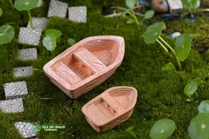 Macro shot of miniature terracotta boats with wood texture on green moss garden