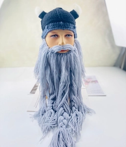 Close-up of creative Viking helmet knitted hat with horns and long grey braided beard
