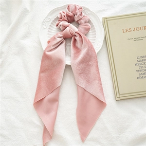 Detail of pink velvet scrunchie with long chiffon ribbons on an artistic background