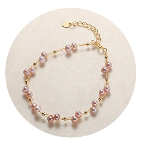 Pink freshwater pearl bracelet with gold metal beads and heart pendant on beige fabric
