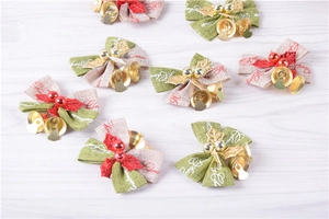 Flat lay view of mini Christmas bows with golden bells and red berries on wooden desk